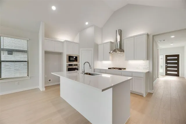 a large kitchen with stainless steel appliances a sink stove and cabinets