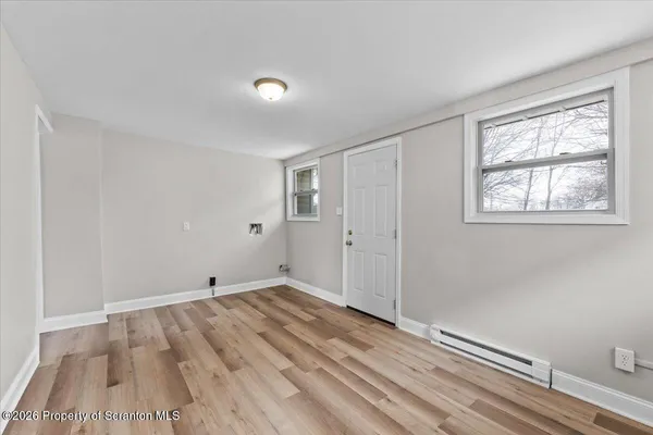 a view of an empty room with wooden floor and a window