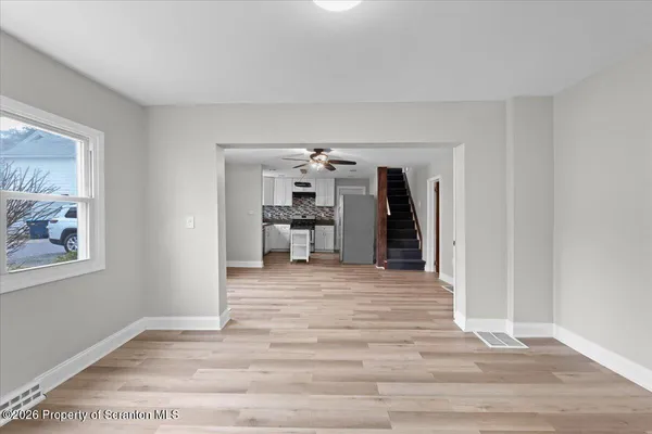 a view of a hallway with wooden floor and a living room