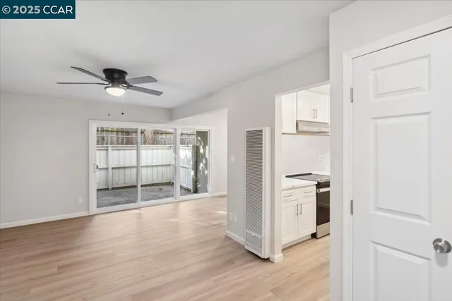 an empty room with wooden floor and a ceiling fan