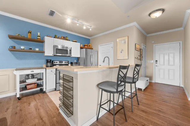 a kitchen with stainless steel appliances a stove a sink dishwasher and a refrigerator with wooden floor