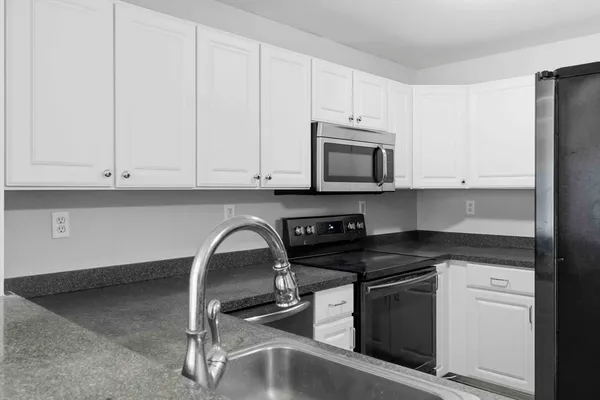 a kitchen with granite countertop white cabinets and black appliances