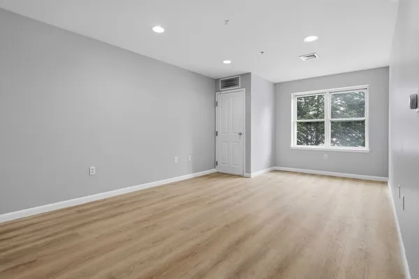 a view of an empty room with wooden floor and windows