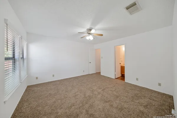 an empty room with chandelier fan and windows