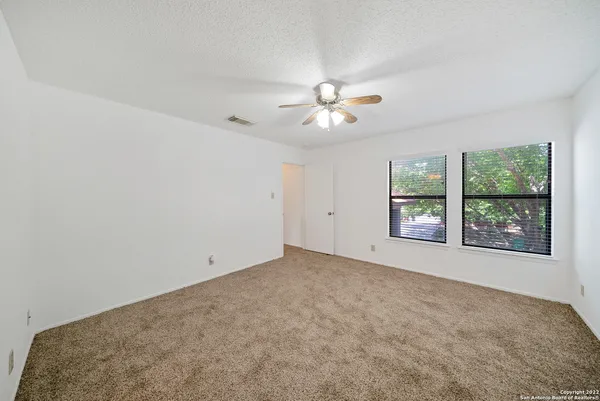 an empty room with windows and ceiling fan