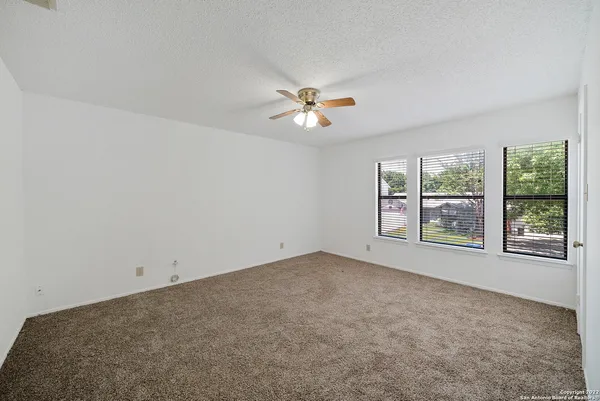 an empty room with windows and chandelier fan