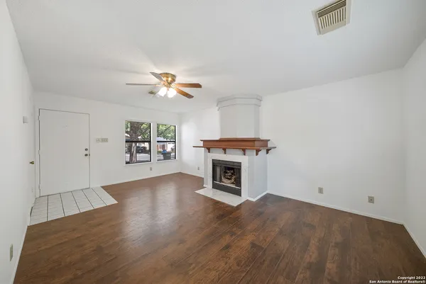 an empty room with a fireplace and a ceiling fan