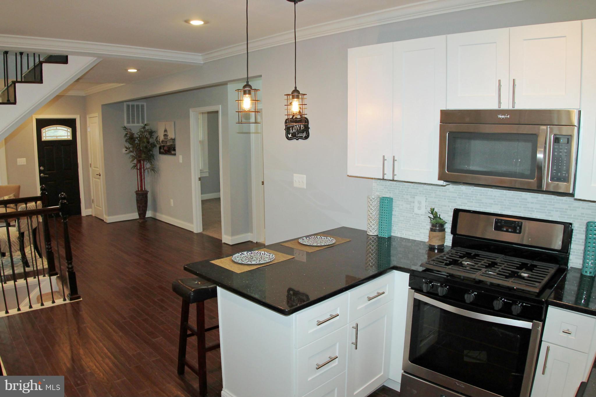 5510 Tramore Road Baltimore, MD 21214 - Photo 12 of 30 a kitchen with granite countertop a stove cabinets and wooden floor