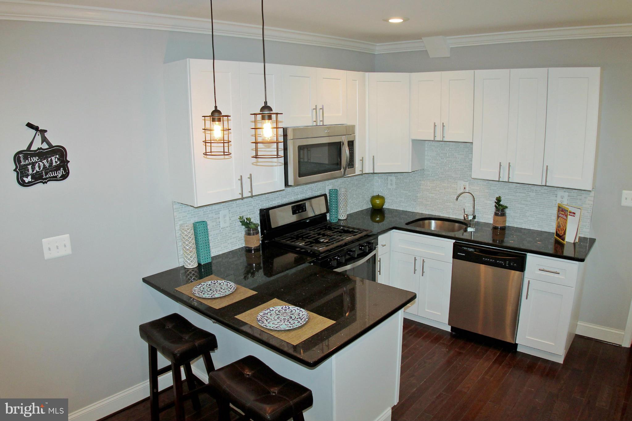 5510 Tramore Road Baltimore, MD 21214 - Photo 10 of 30 a kitchen with stainless steel appliances kitchen island a stove a sink and a microwave