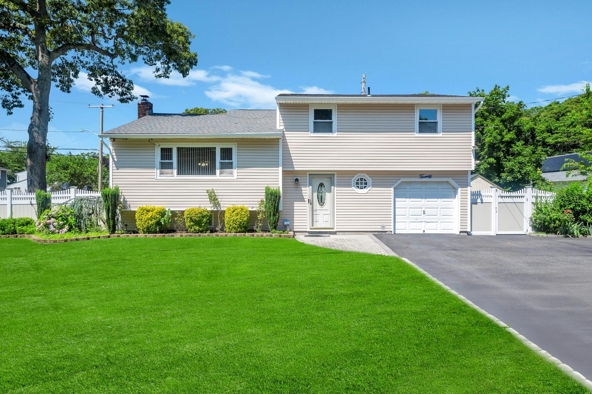 Split level home with a garage, a chimney, and asphalt driveway