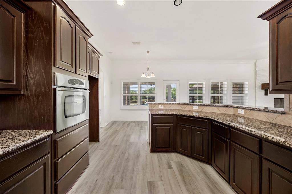 528 Hubbard Circle Nevada, TX 75173 - Photo 16 of 36 Kitchen featuring stainless steel oven, a chandelier, dark brown cabinetry, and light wood-type flooring