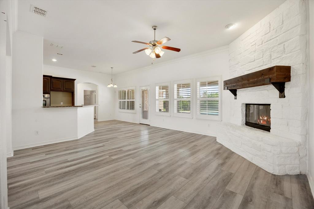 528 Hubbard Circle Nevada, TX 75173 - Photo 22 of 36 Unfurnished living room with a ceiling fan, a fireplace, light wood-style flooring, arched walkways, and ornamental molding