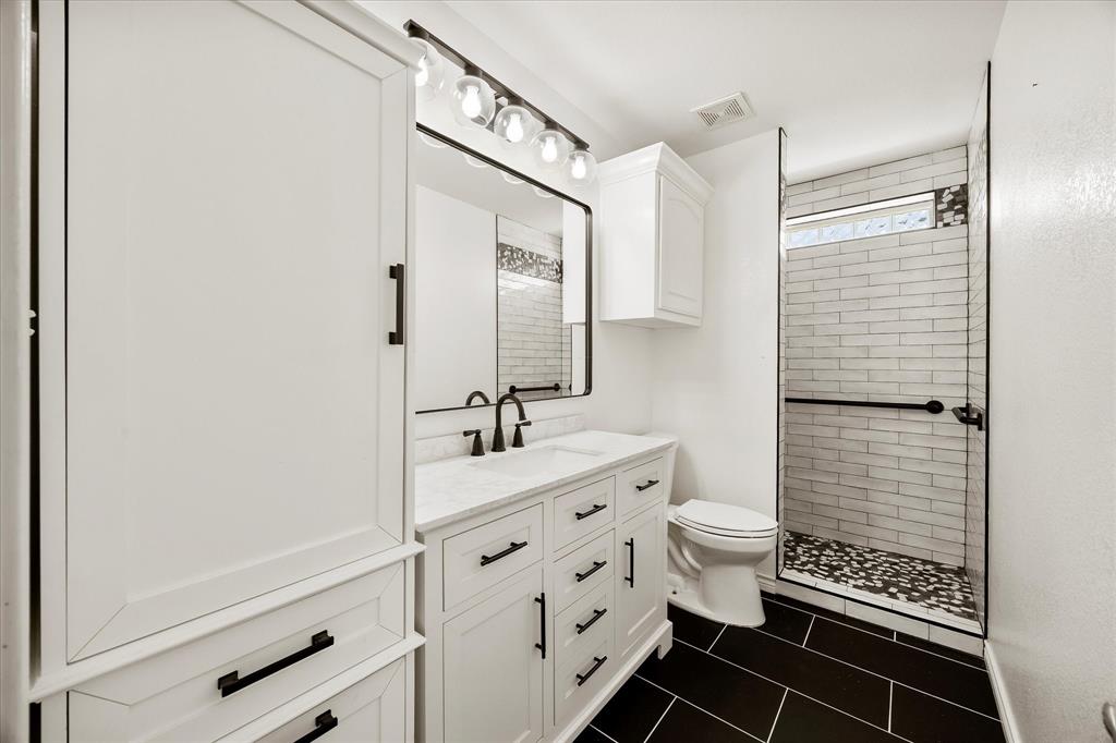 528 Hubbard Circle Nevada, TX 75173 - Photo 27 of 36 Bathroom featuring vanity, tiled shower, tile patterned flooring, and toilet