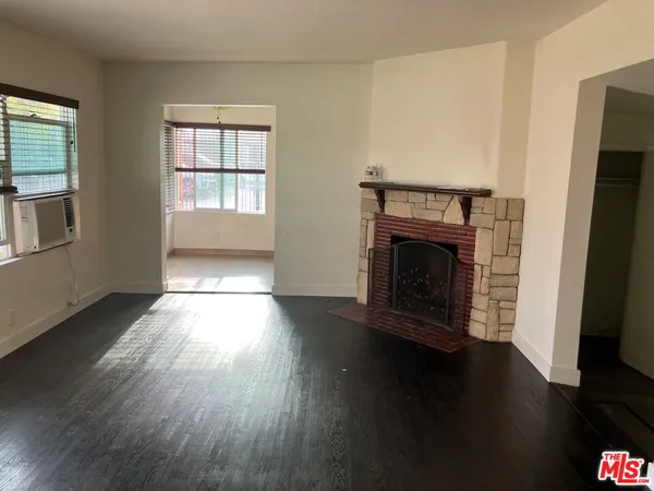 an empty room with wooden floor fireplace and windows