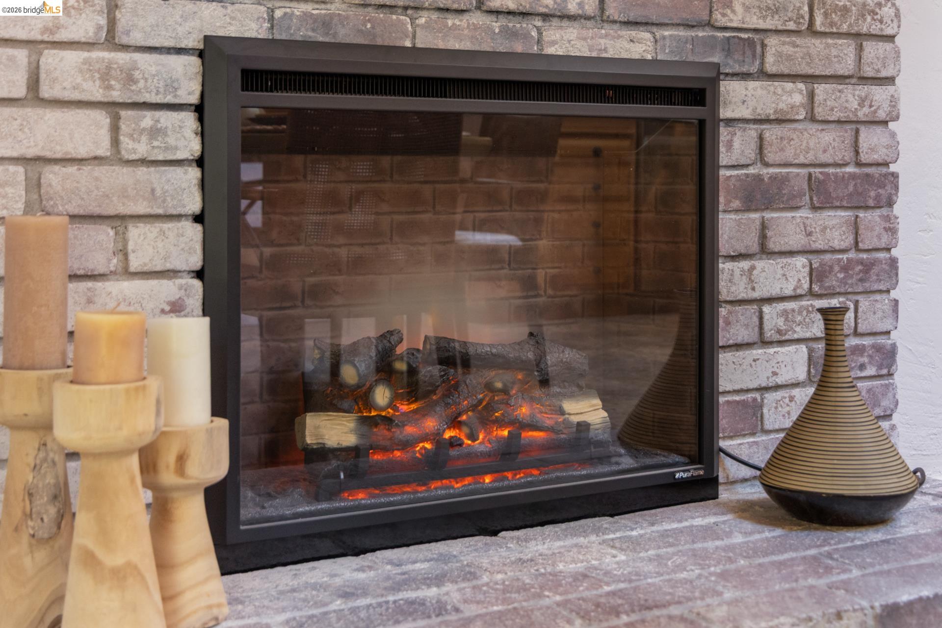 6660 Sobrante Road Oakland, CA 94611 - Photo 13 of 48 Built-in fireplace with a glass front and simulated logs, set within a brick surround and hearth