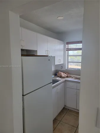 a kitchen with a sink a refrigerator and windows