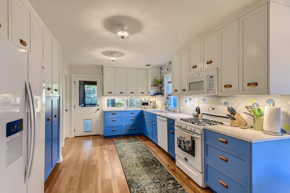 2704 Stacy Lane Austin, TX 78704 - Photo 7 of 15 Kitchen featuring blue cabinetry, white appliances, tasteful backsplash, light wood finished floors, and white cabinetry