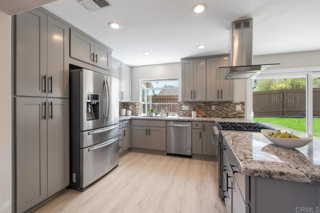 536 Heather Ridge Road San Marcos, CA 92078 - Photo 18 of 66 a kitchen with stainless steel appliances granite countertop a refrigerator a sink dishwasher a stove and white cabinets with wooden floor
