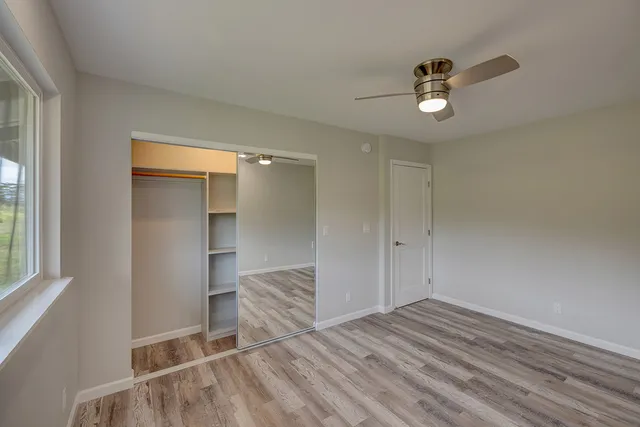 a view of empty room with wooden floor and fan