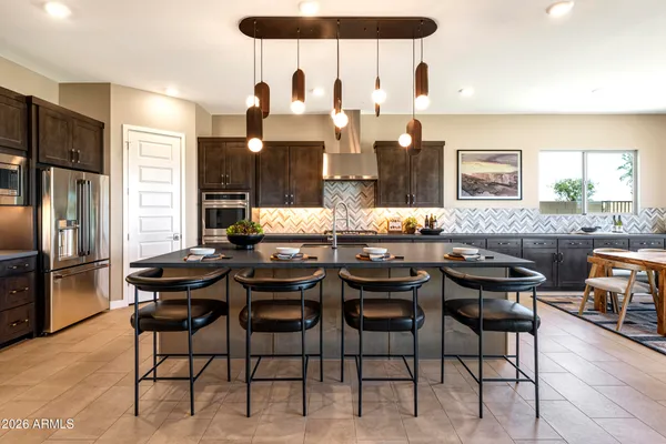 a kitchen with stainless steel appliances kitchen island granite countertop a dining table chairs and a refrigerator