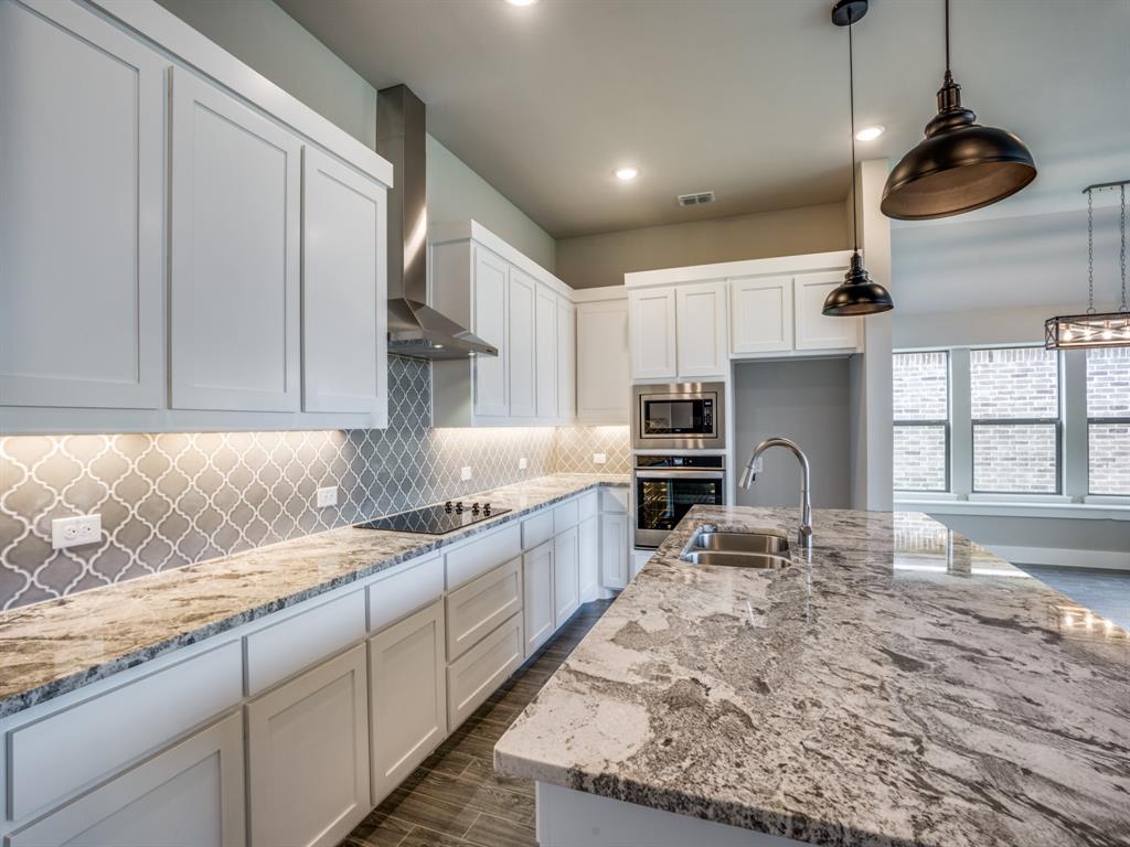 139 Lakeview Circle Pilot Point, TX 76258 - Photo 2 of 19 Kitchen with a sink, stainless steel appliances, wall chimney exhaust hood, decorative backsplash, and light stone countertops