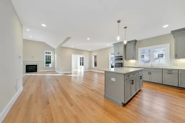 a large kitchen with stainless steel appliances granite countertop a large center island a sink dishwasher a refrigerator and white cabinets with wooden floor