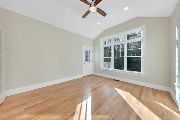 a view of an empty room with a window and wooden floor