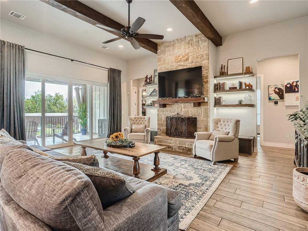132 Huerta Road Florence, TX 76527 - Photo 4 of 40 Exposed wood beams and a natural stone fireplace highlight this inviting living room, opening to an outdoor deck.