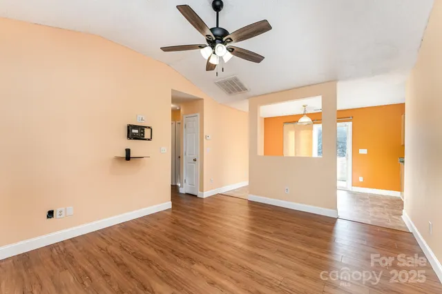 a view of an empty room with window and wooden floor