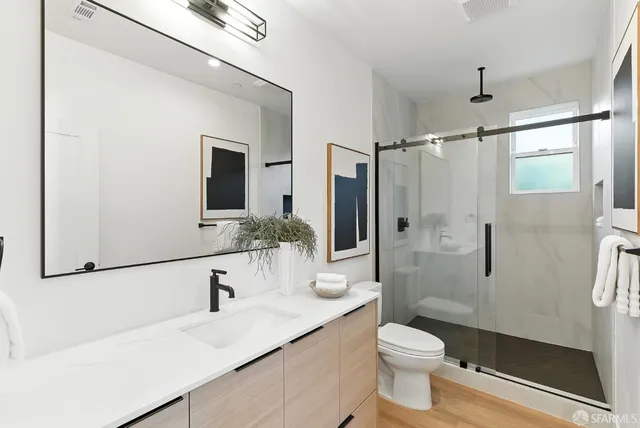 a bathroom with a sink a toilet and shower a mirror