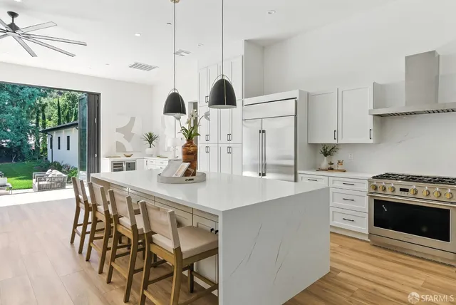 a kitchen with stainless steel appliances a table chairs stove and sink