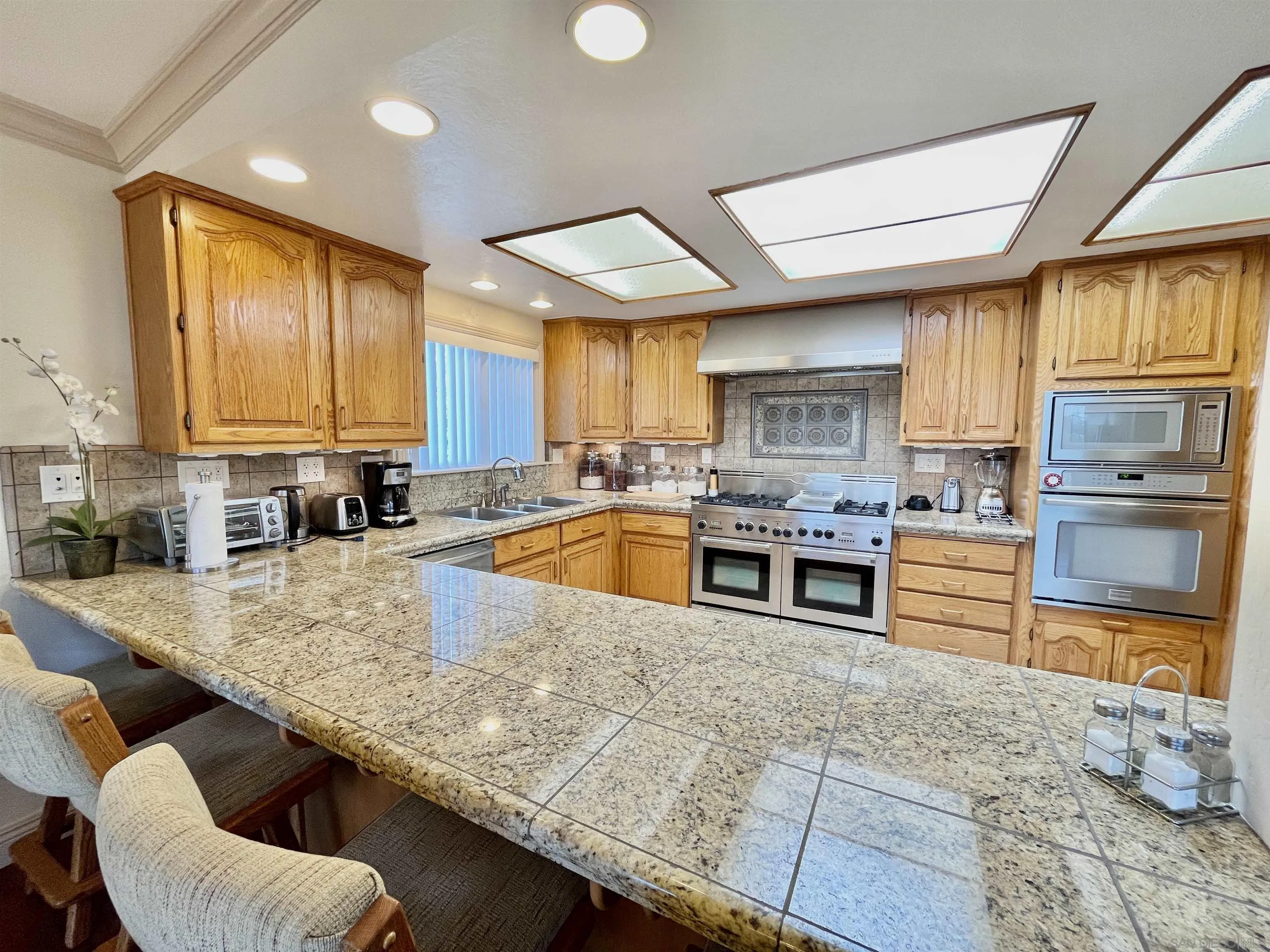8844 Golf Drive Spring Valley, CA 91977 - Photo 11 of 56 a kitchen with stainless steel appliances granite countertop a stove a sink a oven a dining table and chairs