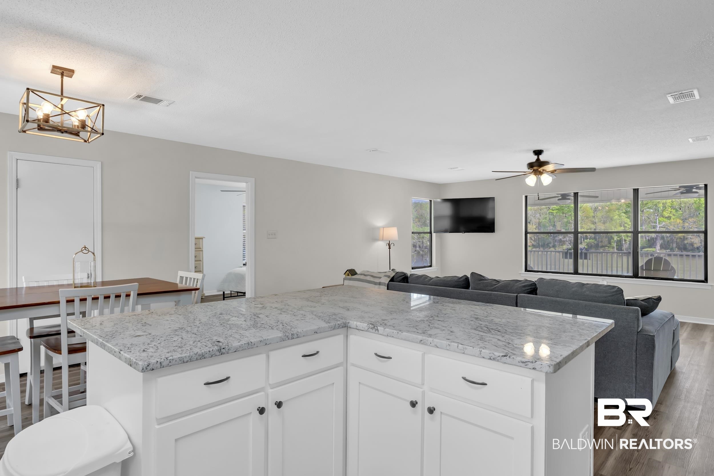 8081 Bryant's Lndg Road Stockton, AL 36579 - Photo 46 of 48 Kitchen with white cabinetry, open floor plan, dark wood-type flooring, light stone countertops, and a center island