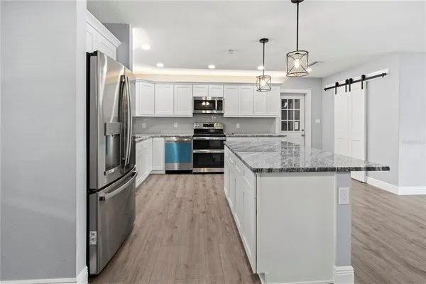 a kitchen with stainless steel appliances granite countertop a refrigerator a oven and a sink