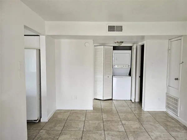 a view of a refrigerator in kitchen and an empty room