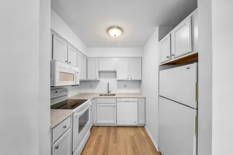 a kitchen with white cabinets and white appliances