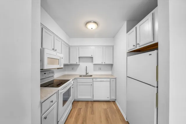 a kitchen with white cabinets and white appliances