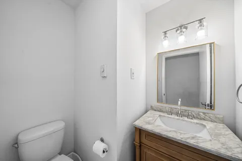a bathroom with a granite countertop sink mirror vanity and toilet