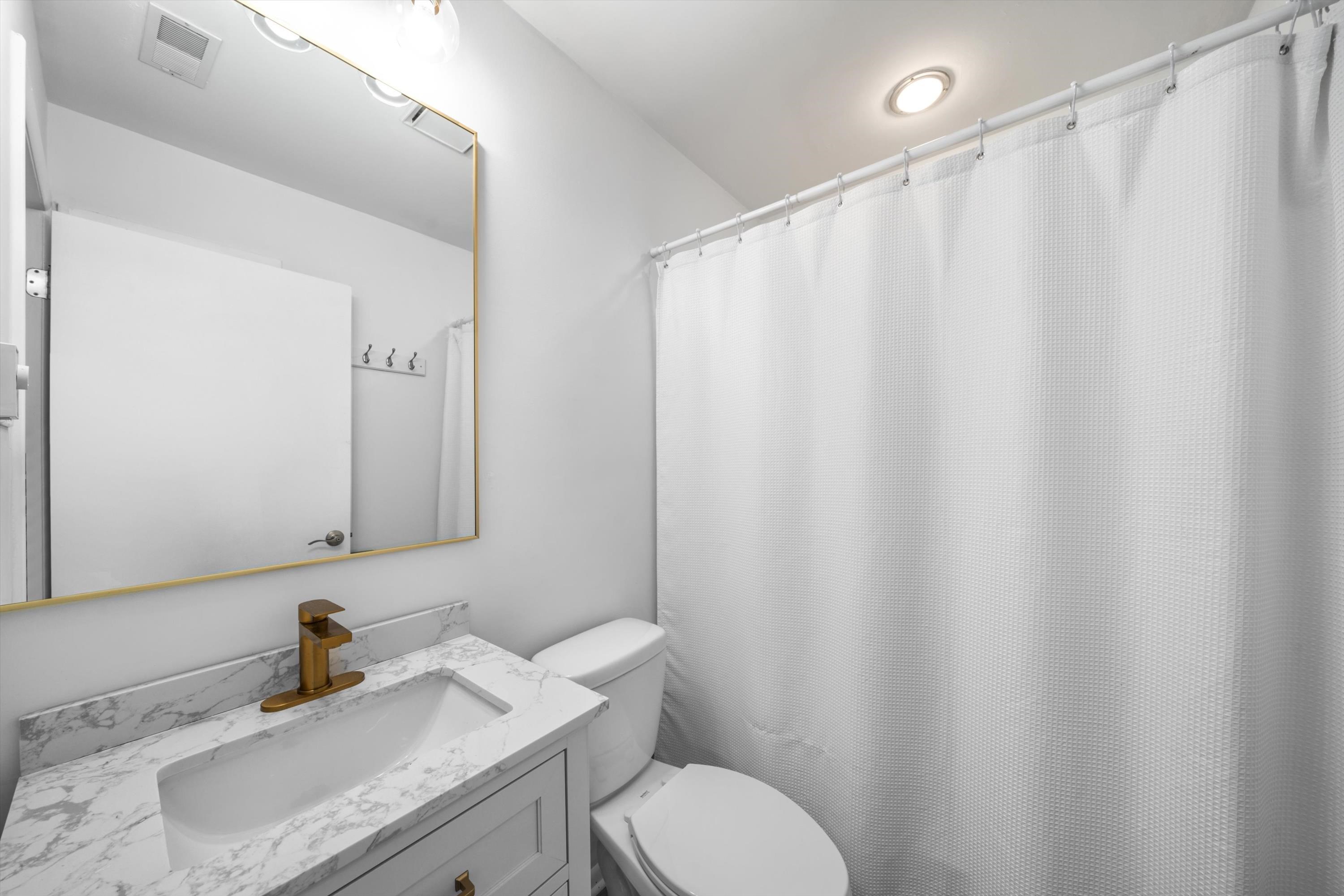 127 40th Street, Unit 1F Sea Isle City, NJ 08243 - Photo 20 of 28 a bathroom with a sink a toilet and shower curtain