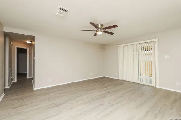 a view of empty room with wooden floor and ceiling fan