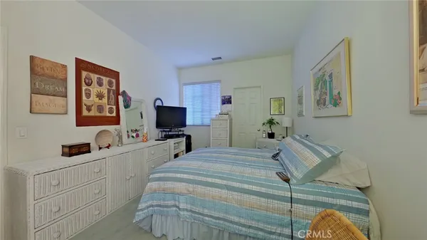 a bedroom with a bed and a flat tv screen on dresser