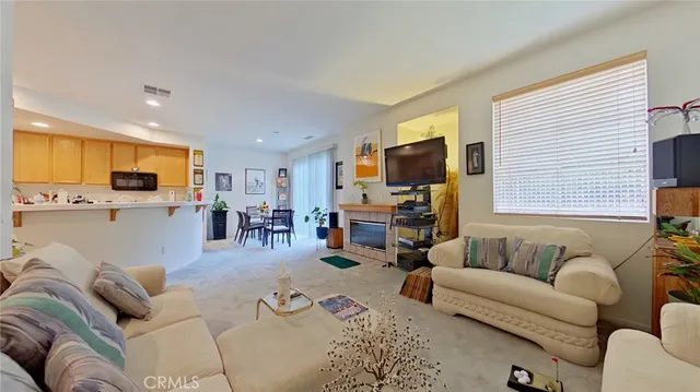 a living room with furniture flat screen tv and kitchen view