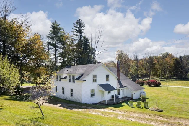a view of a white house with a yard and sitting area