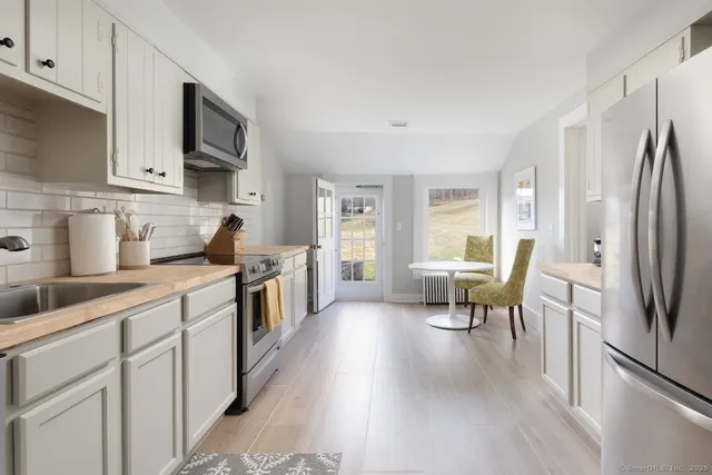 a kitchen with stainless steel appliances a refrigerator a sink dishwasher a stove and white cabinets with wooden floor