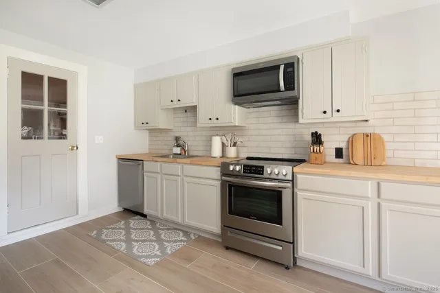 a kitchen with cabinets stainless steel appliances and wooden floor