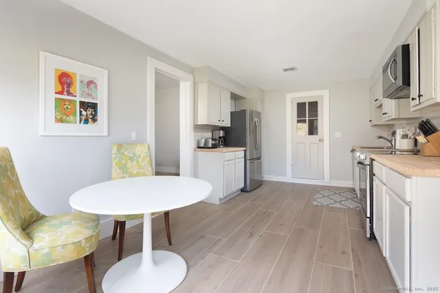a kitchen with stainless steel appliances a dining table chairs and a refrigerator