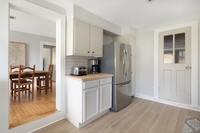 a kitchen with stainless steel appliances granite countertop a refrigerator a stove and a dining table with wooden floor