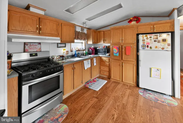 a large kitchen with stainless steel appliances granite countertop a stove a refrigerator a oven with a dining table and chairs with wooden floor