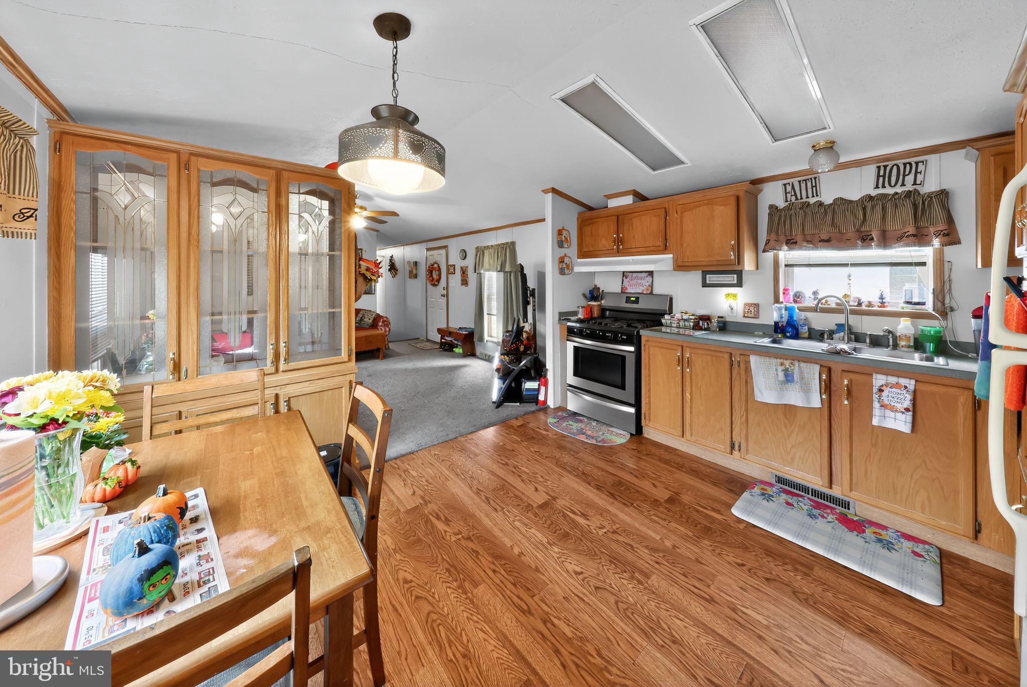 8 Penney Lane Coatesville, PA 19320 - Photo 6 of 14 a large kitchen with stainless steel appliances granite countertop a stove a refrigerator a oven with a dining table and chairs with wooden floor