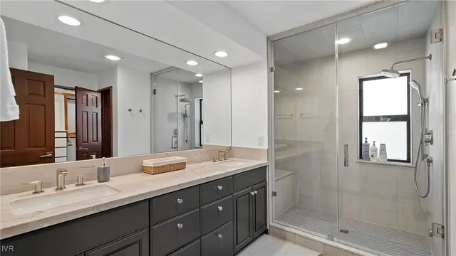 a bathroom with double vanity sinks and a shower